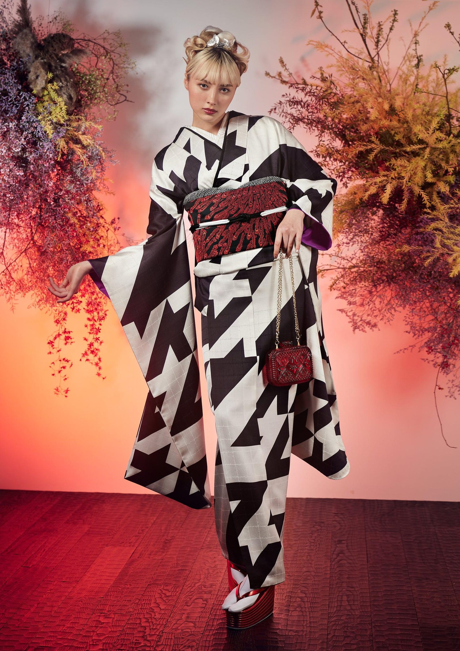 Model in a black and white geometric-print kimono against a red backdrop