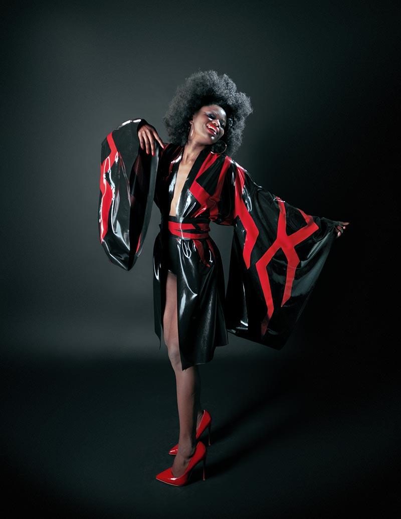 Model in a black kimono with red geometric bands, photographed in low dramatic light